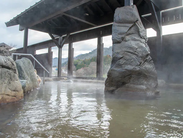 永源寺溫泉八風之湯露天浴池，石造浴槽面向愛知川與山林